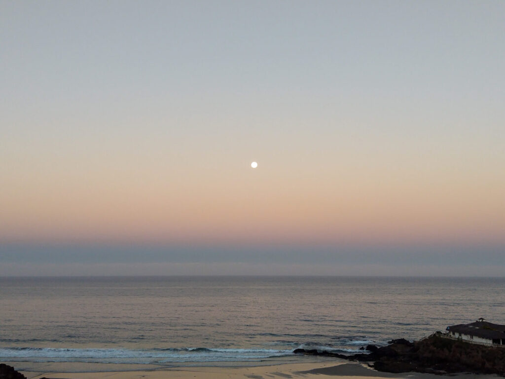 a full-moon in the early hours of morning by the beach.