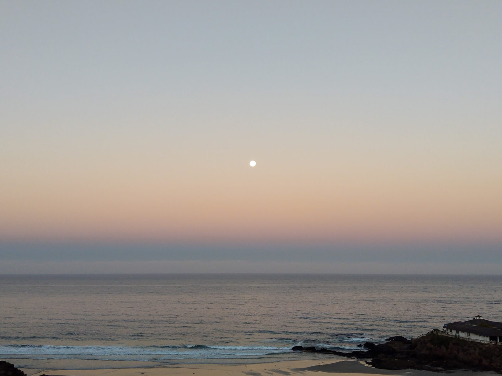 a full-moon in the early hours of morning by the beach.